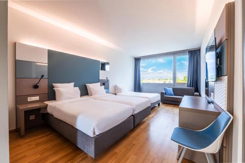 ein Hotelzimmer mit 2 Betten und einem Schreibtisch in der Unterkunft B&B HOTEL Lausanne Crissier in Lausanne