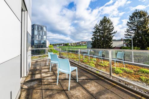 a balcony with three chairs and a view of a building at B&B HOTEL Lausanne Crissier in Lausanne