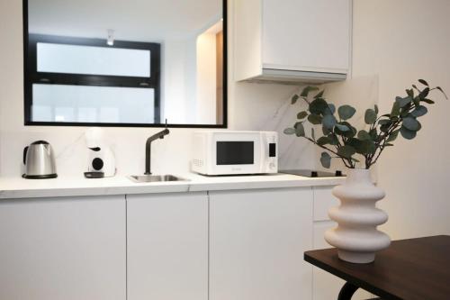 une cuisine blanche avec un four micro-ondes et un vase avec une plante dans l'établissement Logement Idéal en Famille - Porte du Marais - 6P - FLAT-GUEST, à Paris