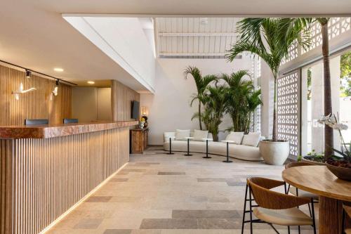 a lobby with a bar with white furniture and palm trees at Wyndham Santa Marta Aluna Beach in Santa Marta