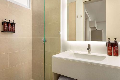 a bathroom with a shower with a sink and a mirror at Wyndham Santa Marta Aluna Beach in Santa Marta