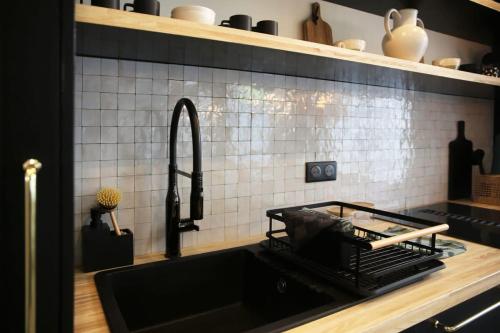 une cuisine avec un évier et un plan de travail noir dans l'établissement Appartement familiale sauna Paris 10 - 8P - FLAT-GUEST, à Paris