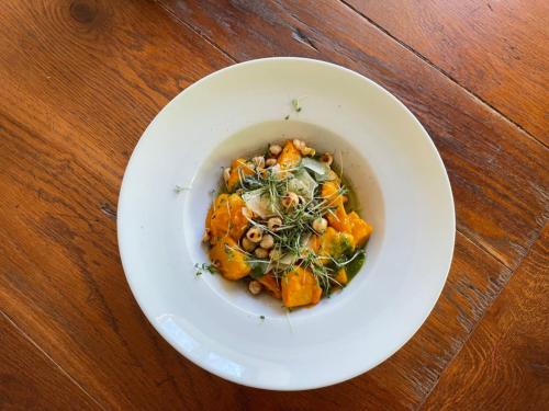 a white bowl of food on a wooden table at Gasthaus Fischerrosl in Münsing am Starnberger See