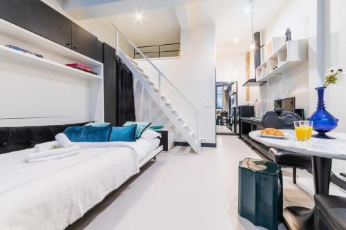 un salon avec un grand lit blanc et une table à manger dans l'établissement Studio refait a neuf a montorgueil - Paris 2 - FLAT-GUEST, à Paris