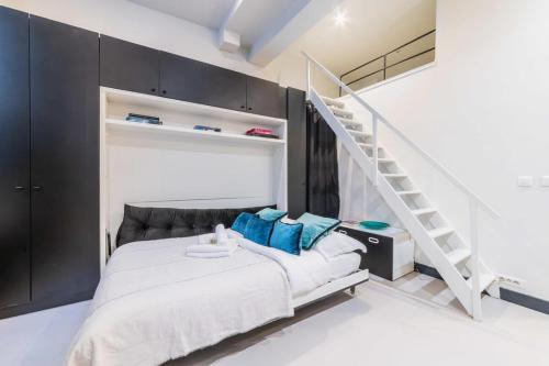 - une chambre avec un lit doté d'oreillers bleus et un escalier dans l'établissement Studio refait a neuf a montorgueil - Paris 2 - FLAT-GUEST, à Paris