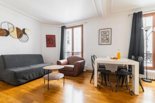 un soggiorno con divano e tavolo di 85m2 de Confort Paris 17 - Charme parisien 6P a Parigi