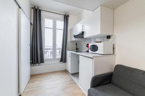 een kleine keuken met een bank en een magnetron bij Studio mezzanine proche Zenith - Paris 19 - 2P in Parijs
