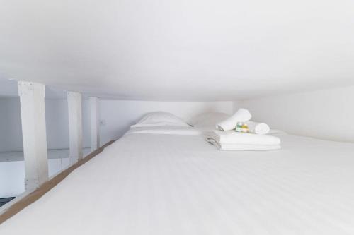 uma cama branca num quarto branco com mobiliário branco em Studio mezzanine proche Zenith - Paris 19 - 2P em Paris