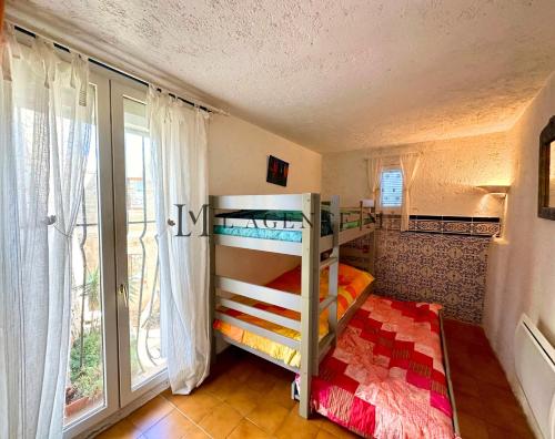 une chambre avec deux lits superposés et une fenêtre dans l'établissement Maison de village typique bord de mer ALGAJOLA, à Algajola