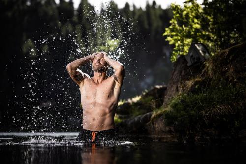 a shirtless man standing in the water with his hands on his head at Hotel Hochschober in Turracher Hohe