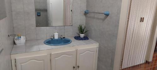 a bathroom with a blue sink and a mirror at Cicada's Call Guest Cottage in Nelspruit