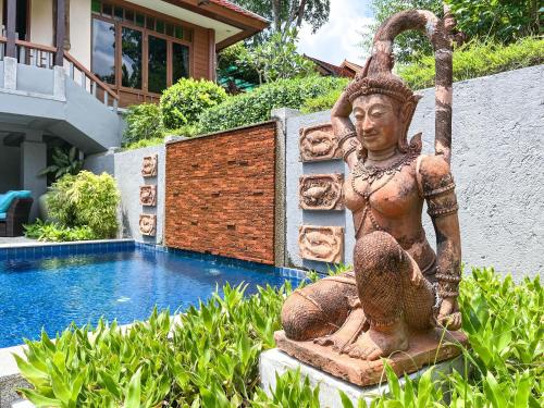 une statue assise à côté d'une piscine dans l'établissement Baleeyan Residence, à Thalang