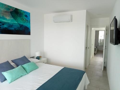 a white bedroom with a bed with blue pillows at Nunoli Duplex Luxury Playa Blanca in Playa Blanca