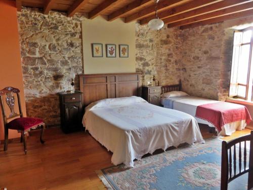 a bedroom with two beds and a stone wall at Casa Rural A Pasada in Cedeira