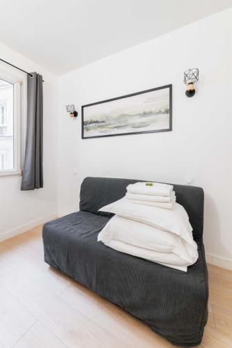 - un lit noir dans une chambre blanche avec une photo sur le mur dans l'établissement Studio proche sacre cœur - Paris 9 -2P - FLAT-GUEST, à Paris