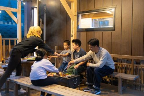 um grupo de pessoas sentadas em torno de uma mesa em um restaurante em CampBaseKadojin - Vacation STAY 73760v em Tenkawa