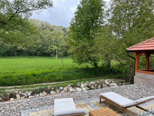 a patio with a gazebo and two white chairs at Vip kuca Banja Vrujci in Popadić