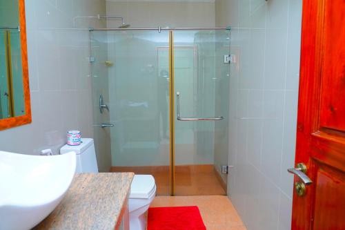 La salle de bains est pourvue d'une douche en verre et de toilettes. dans l'établissement Tilko City Hotel Jaffna, à Jaffna