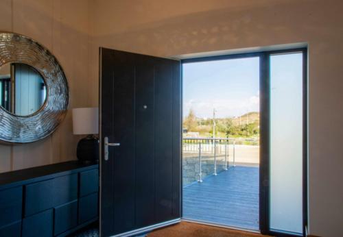 a door to a room with a view of a deck at Sruthan Pier House in Carraroe