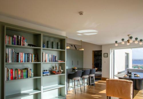 a living room with bookshelves and a table with chairs at Sruthan Pier House in Carraroe