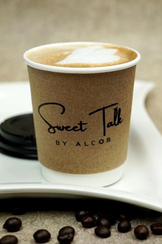a cup of coffee on a plate with coffee beans at The Alcor Hotel in Jamshedpur