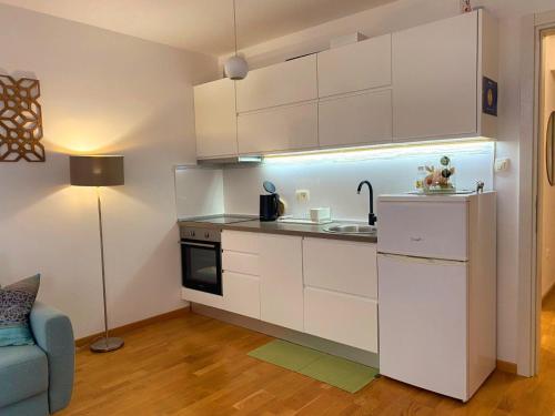 a kitchen with white cabinets and a sink and a couch at Apartments Fontana 20 in Budva