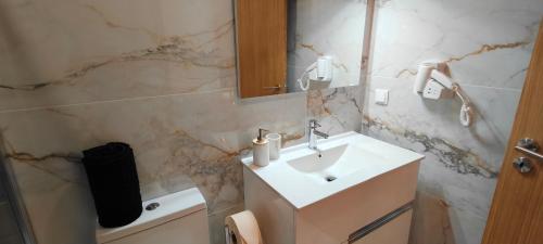 La salle de bains est pourvue d'un lavabo blanc et d'un miroir. dans l'établissement Suíte Leonor, à Alijó