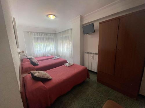 a hotel room with two beds and a television at Hostal Cumbre in Zaragoza
