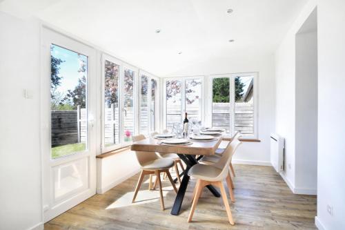 une salle à manger avec une table, des chaises et des fenêtres dans l'établissement L'Eden E&M - Belle maison 8 voyageurs, à Portbail