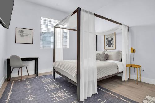 um quarto com uma cama de dossel e uma secretária em Hinds by AvantStay Duplex in North Hollywood em Los Angeles