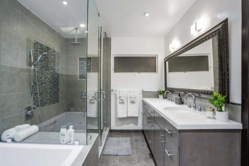 uma casa de banho com 2 lavatórios, um chuveiro e uma banheira. em Walefield by AvantStay Mid-Wilshire Home Pool em Los Angeles