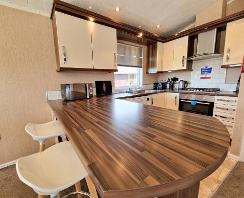 a kitchen with a wooden counter top and white chairs at Benarty 11 with Private Hot Tub - Fife - Loch Leven - Lomond Hills - Pet Friendly in Kelty