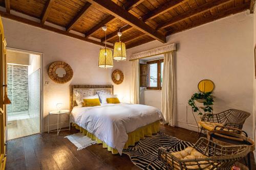 um quarto com uma cama, uma cadeira e janelas em Casa Bernarda with Heated Pool em La Cisnera
