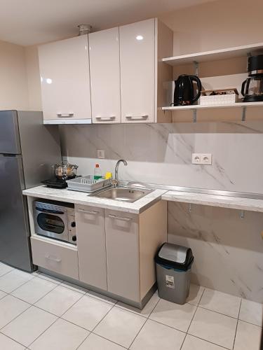 a kitchen with white cabinets and a sink and a refrigerator at Rooms Anastasia Paralia in Paralia Katerinis