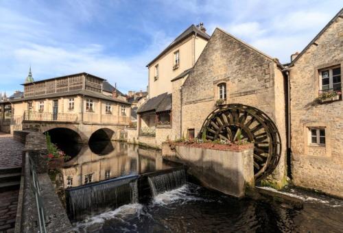 un fiume con mulino ad acqua in una città con edifici di Camélia a Bayeux