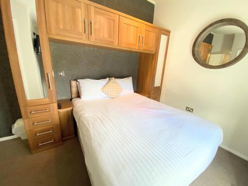 a bedroom with a white bed with a wooden cabinet and a mirror at Benarty 11 with Private Hot Tub - Fife - Loch Leven - Lomond Hills - Pet Friendly in Kelty