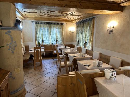 un comedor con mesas, sillas y ventanas en B&B Meublè Giustina, en Auronzo di Cadore