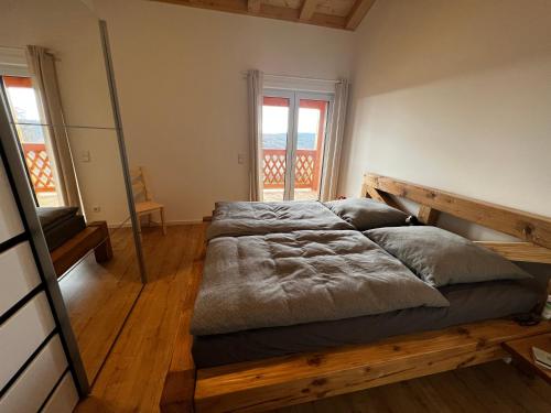 ein großes Bett in einem Zimmer mit Holzböden und Fenstern in der Unterkunft Ferienwohnung Waldblick in Sinzing