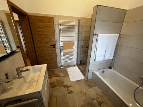 ein Bad mit einer Badewanne, einem Waschbecken und einer Dusche in der Unterkunft Ferienwohnung Waldblick in Sinzing