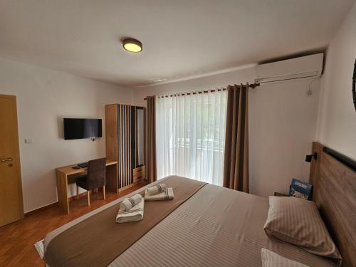 Schlafzimmer mit einem Bett, einem Schreibtisch und einem TV in der Unterkunft Dom M Apartments in Budva