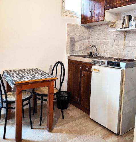 a kitchen with a small table and a white refrigerator at Eleni Apartments Sant George Beach in Agios Georgios