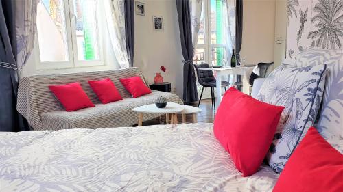a bedroom with a bed and a couch with red pillows at Petit Ecrin à migennes balcon-gare-clim in Migennes
