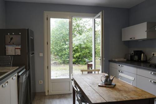 une cuisine avec une table en bois et une grande fenêtre dans l'établissement Maison 8 personnes, à Mézos