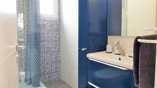 y baño azul con lavabo y ducha. en Petit Ecrin à migennes balcon-gare-clim en Migennes