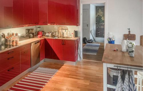 博里霍尔姆2 Bedroom Lovely Apartment In Borgholm的铺有木地板的厨房配有红色橱柜