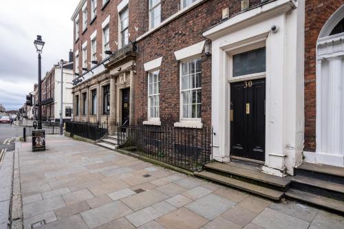 een bakstenen gebouw met een zwarte deur op een straat bij Rodney Street Luxury Townhouse & Apartments, Central & Stylish in Liverpool
