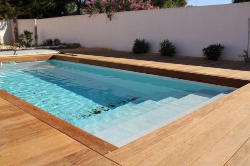 a swimming pool with a wooden floor and a wooden deck at Chez Diane - Luxueuse Villa avec piscine et plage à proximité in La Grande-Motte
