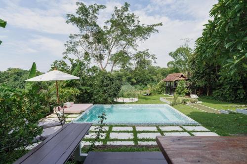 a swimming pool with a bench and an umbrella at Riverside Pool Villa - Nature Escape - Chiang Mai in Ban Don