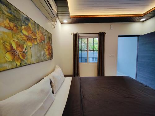 een slaapkamer met een bed en een schilderij aan de muur bij Kevin's House by TravelKrafts in Anjuna