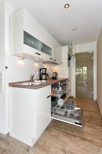 a white kitchen with a sink and a dishwasher at Residenz Waterkant in Bensersiel
